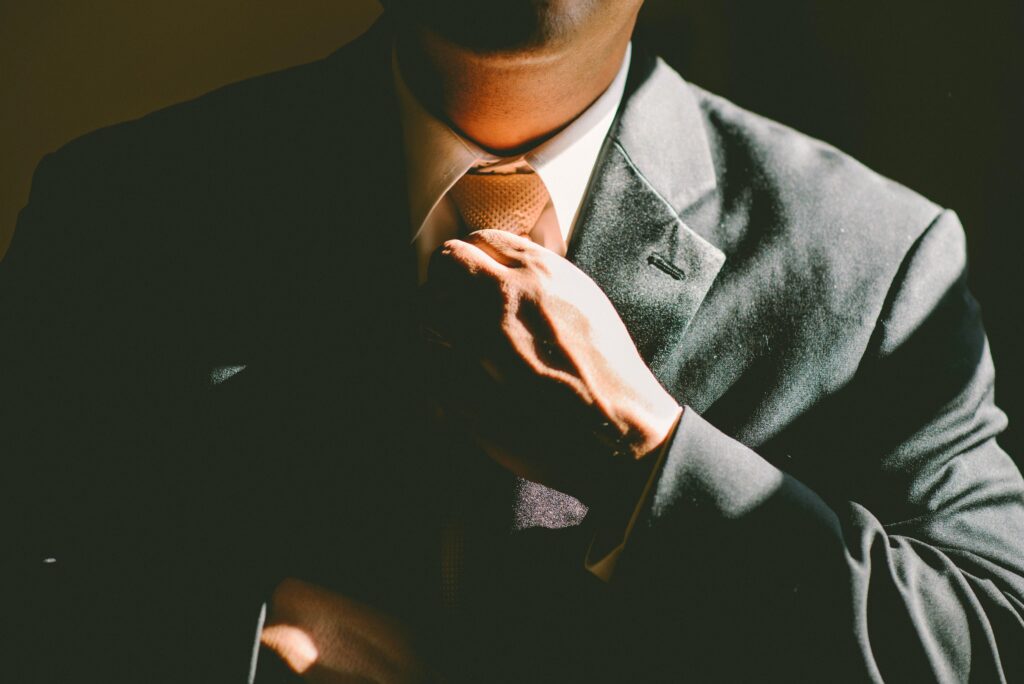 Private equity professional wearing suit and adjusting tie.